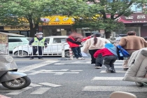 老人抱小孩在马路中间参与护学岗 网友热议安全隐患